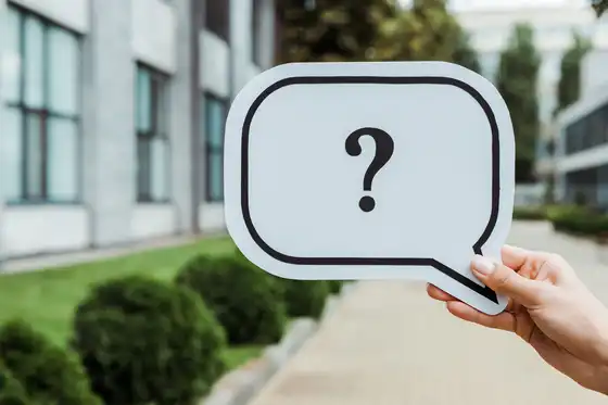 Eine Hand, die ein Schild mit einem Fragezeichen in einer Sprechblase hält
